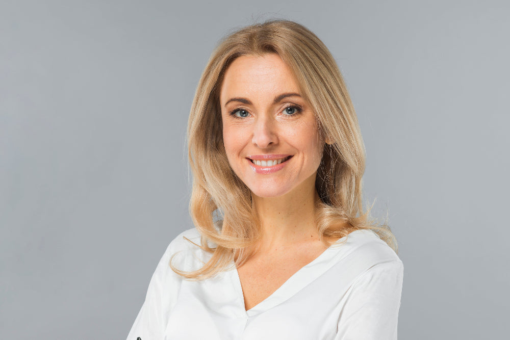 Woman with blonde hair and a white shirt against a gray background