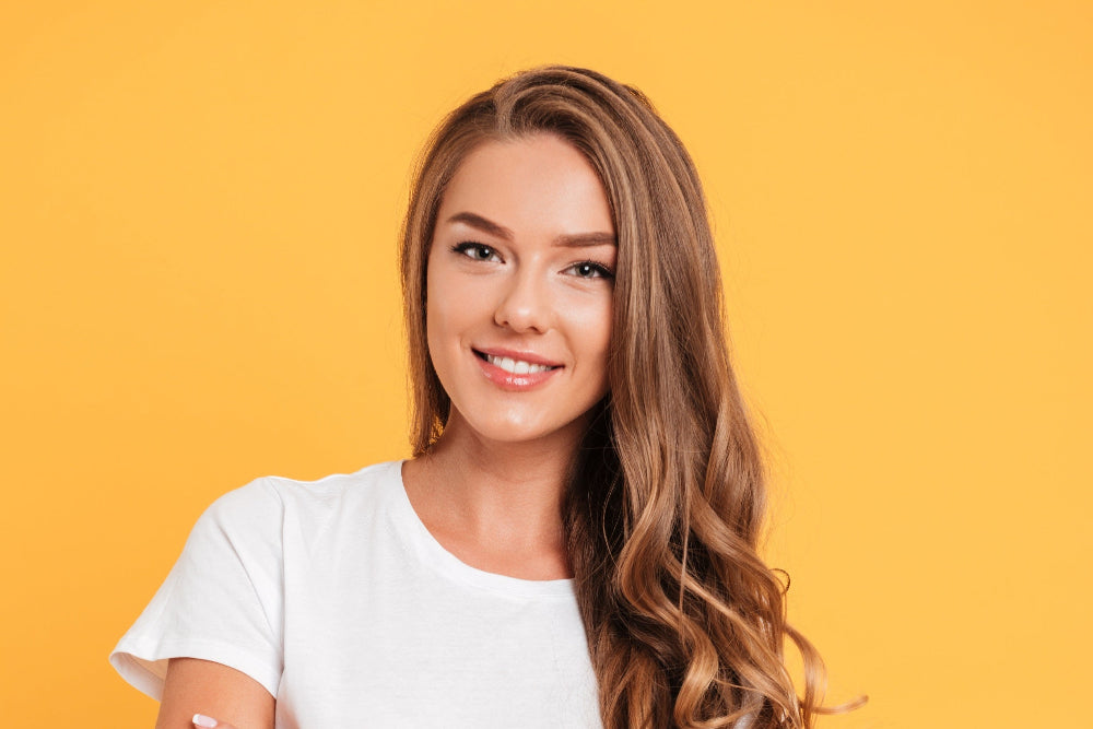 Woman with long hair wearing a white t-shirt on a yellow background